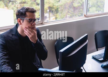 Man with computer with doubt face. Blond Caucasian man who works in an office with a window behind him. Man working with question face. High quality photo Stock Photo