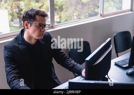 Man with a confused face working on the computer. Man in an office using the computer while looking at it with a very confused look. High quality photo. Man working with electronics Stock Photo