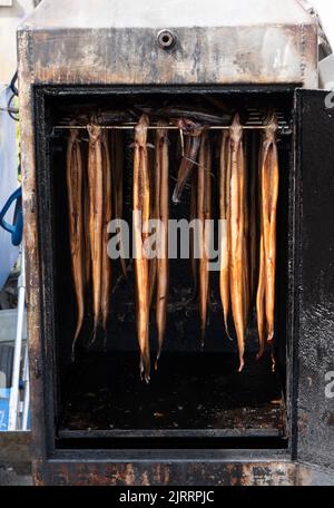 smoked eel hang in a smoker ready to be sold and eaten Stock Photo