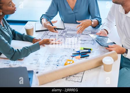 Blueprints, architects and building engineers talking, meeting and planning renovation, remodeling or floor plan with tablet. Diverse group of Stock Photo