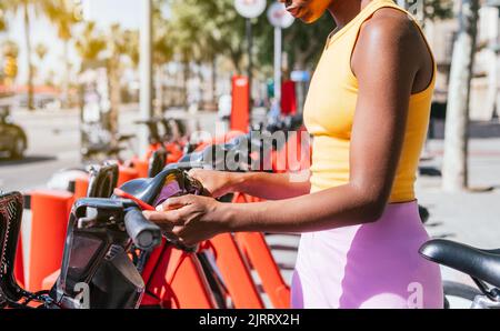 unrecognizable african woman using her phone to use public system of bicycle renting Stock Photo