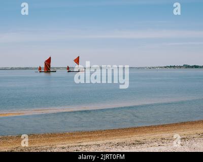 Two historic red sailed Thames Sailing Barges heading out along the Blackwater estuary at Bradwell Waterside, Bradwell On Sea, Essex England UK Stock Photo