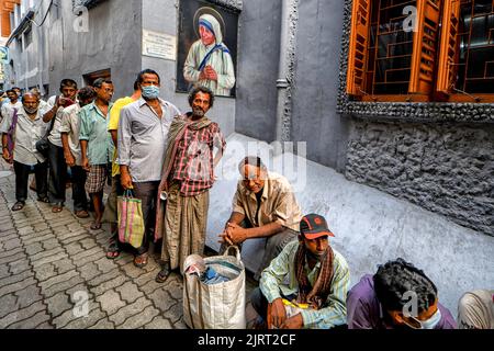 Kolkata, India. 26th Aug, 2022. Underprivileged people stand in queues under a picture of Mother Teresa, to receive food packets being distributed by the nuns from the Catholic Order of the Missionaries of Charity after special prayers held at the tomb of Teresa to mark her 112th Birth Anniversary at the Mother House in Kolkata. Mother Teresa, known in the Catholic Church as Saint Teresa of Calcutta, devoted her life to caring for the sick and poor lives throughout the world & canonised by the Roman Catholic Church as Saint Teresa. Credit: SOPA Images Limited/Alamy Live News Stock Photo