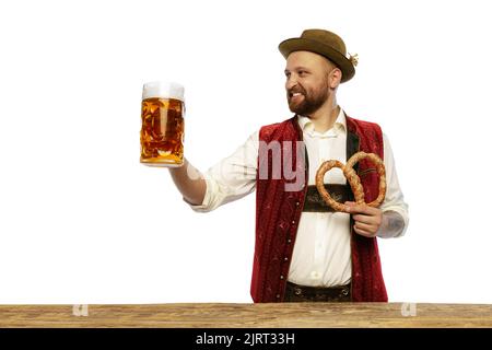 Portrait of young man wearing traditional Bavarian or German clothes isolated over white background. Pretzel and beer mug Stock Photo