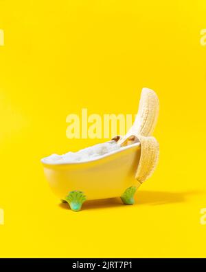 Funny banana relaxing in the bathtub on the yellow background. Holiday concept idea. Stock Photo