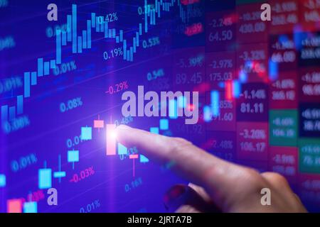 The trader points his finger at the Rising stock chart on the monitor Stock Photo