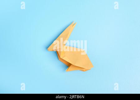 Origami Bunny. Step-by-step photo instruction on a blue background. Easter bunny. DIY concept. Step14. Rabbit 2023. Stock Photo