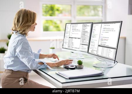 Programmer Woman Coding On Multiple Computer Screens Stock Photo