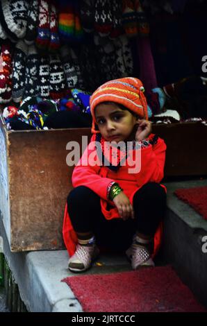 Children nepalese girl people sitting alone wait friends go to playing in Halloween festive and diwali festival celebration of lights in street market Stock Photo