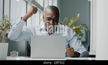 African excited happy businessman american executive agent programmer investor win online lottery commercial bet profit celebrate career growth Stock Photo
