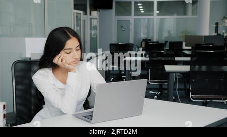 Bored lazy arabian businesswoman upset female clerk sits at office has problem stress. African active colleague man cheering up passive friend ask to Stock Photo