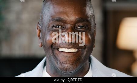 Happy emotional african american adult man sincere smiling laughing loud indoors head shot of mature senior pensioner grandpa laugh over humorous joke Stock Photo