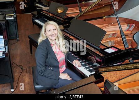 Hamburg, Germany. 25th Aug, 2022. Yvonne Trübger, owner, sits at a grand piano during a photo session to celebrate the 150th anniversary of Pianohaus Trübger. The piano house is one of the last piano houses that does not represent only one brand. (to dpa 'Pianohaus Trübger gives away 15 pianos for 150th anniversary') Credit: Georg Wendt/dpa/Alamy Live News Stock Photo