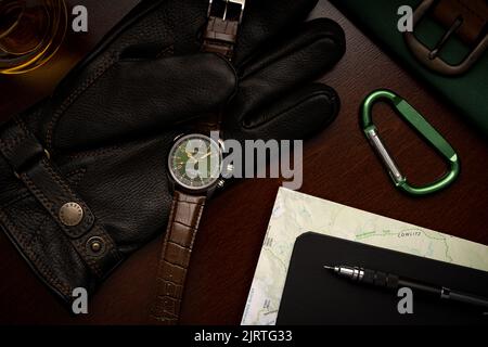 Top view of expensive luxury Seiko Alpinist Green men's watch with various accessories on dark wooden table Stock Photo