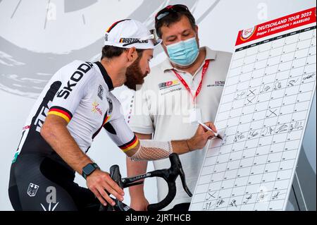 Meiningen, Germany. 26th Aug, 2022. Cycling: Tour of Germany, Meiningen - Marburg (200.70 km), stage 2. Simon Geschke (l) of the German national team signs up for the start of the second stage. Credit: Daniel Vogl/dpa/Alamy Live News Stock Photo