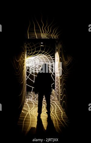 Silhouette of a woman standing in a dark glowing patterned corridor Stock Photo