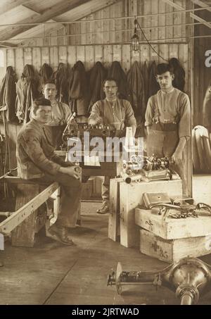 Four unidentified WWI working on an engine in a mechanical engineering workshop at Oatlands Park, Surrey, England, 1918, England, maker unknown. Acquisition history unknown. Stock Photo