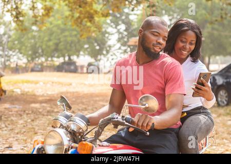 african lady on a bike and the rider view content on phone Stock Photo