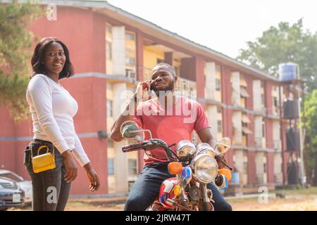 african bike man standing with a lady making a call Stock Photo