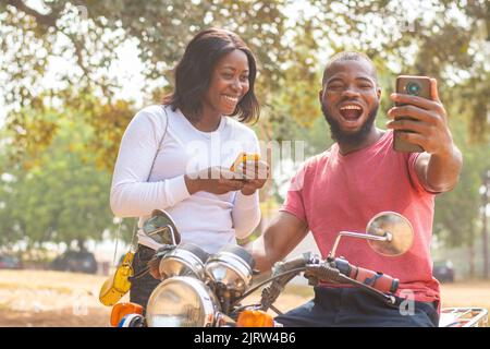 african man and woman look at phone excitedly Stock Photo