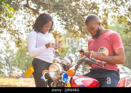 african man and woman sharing content from their phones Stock Photo