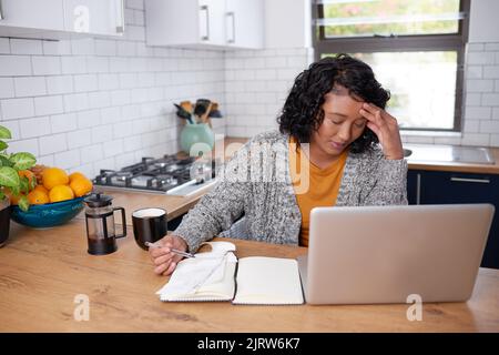 A young multi-ethnic woman is stressed while calculating household expenses Stock Photo