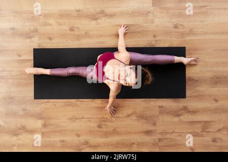 woman doing yoga exercise on mat at studio Stock Photo