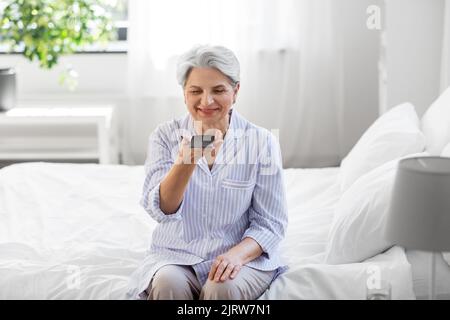 happy senior woman recording voice on smartphone Stock Photo