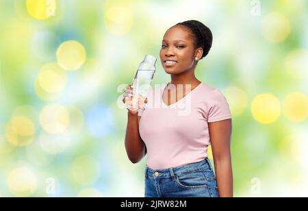 happy african woman drinks water from glass bottle Stock Photo