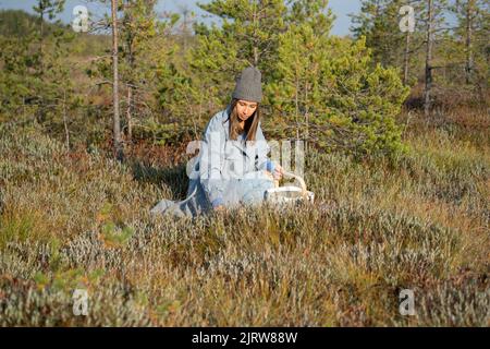 Autumn berries picking. Young woman on swamp searching for ripe cranberry spend weekend outside city Stock Photo