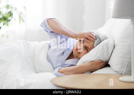 senior woman with headache in bed at home Stock Photo