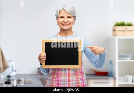 smiling senior woman with chalkboard at kitchen Stock Photo
