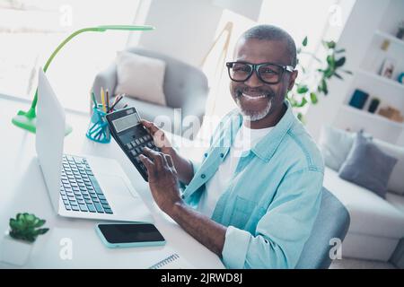 Photo of middle aged man investor count tax funds using netbook calculator sit desk in modern workplace indoors Stock Photo