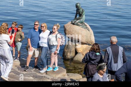 Tourists in Copenhagen Denmark visiting the bronze sculpture of the Little Mermaid by Edvard Eriksen on the Langelinie promenade by the city's harbour