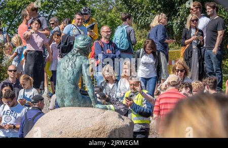 Tourists in Copenhagen Denmark visiting but largely ignoring the bronze sculpture of the Little Mermaid by Edvard Eriksen by the city's harbour