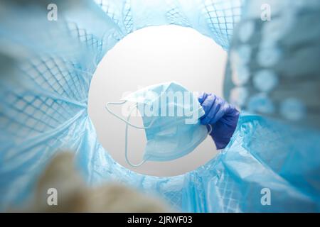 hand throwing used medical mask into trash can Stock Photo