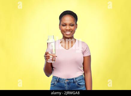 happy african woman drinks water from glass bottle Stock Photo