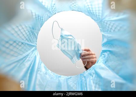 hand throwing used medical mask into trash can Stock Photo