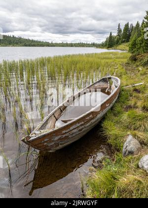 Scuppered wooden rowing boat by a mountain lake in central Norway Stock Photo