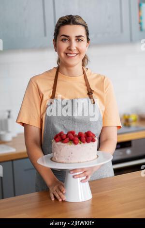 happy woman with raspberry cake on kitchen at home Stock Photo