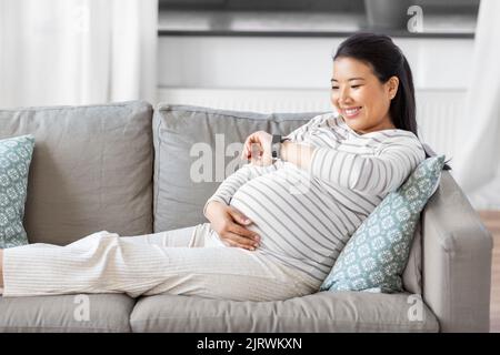 happy pregnant woman with smart watch at home Stock Photo