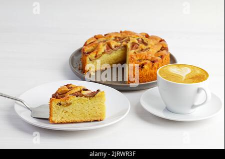 Closeup homemade fig pie and cup of coffee on white wooden table. Shallow focus on piece of pie. Stock Photo
