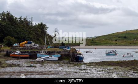 Clonakilty, Ireland, July 2, 2022. An old jetty and several moored fishing boats in Clonakilty Bay. Fishing boats anchored at low tide. Shallow sea, l Stock Photo