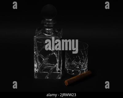 Crystal glass and whisky bottle with a Cuban cigar on black background Stock Photo