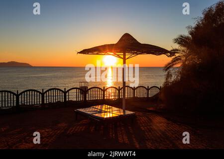 Sun umbrellas and chaise lounges on tropical beach at sunrise. Concept of rest, relaxation, holidays, resort Stock Photo