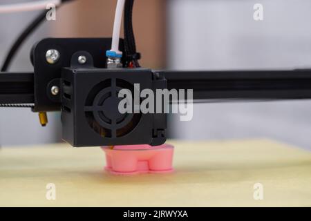 Print head of 3D printer machine printing pink plastic model - close up Stock Photo
