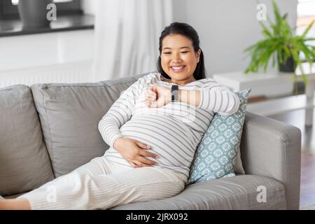 happy pregnant woman with smart watch at home Stock Photo