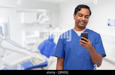smiling doctor using smartphone at dental office Stock Photo