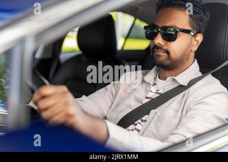 smiling indian man in sunglasses driving car Stock Photo