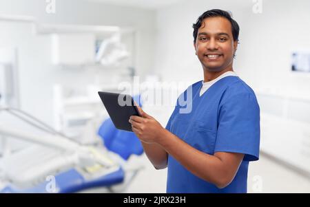 smiling doctor using tablet pc at dental office Stock Photo